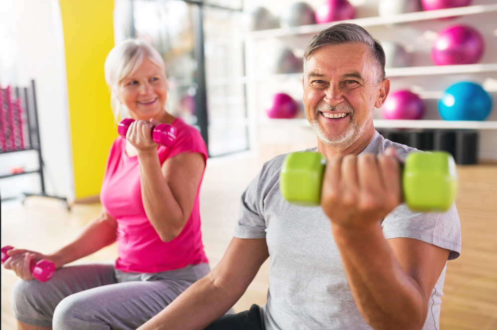 older man and woman curling light colorful weights